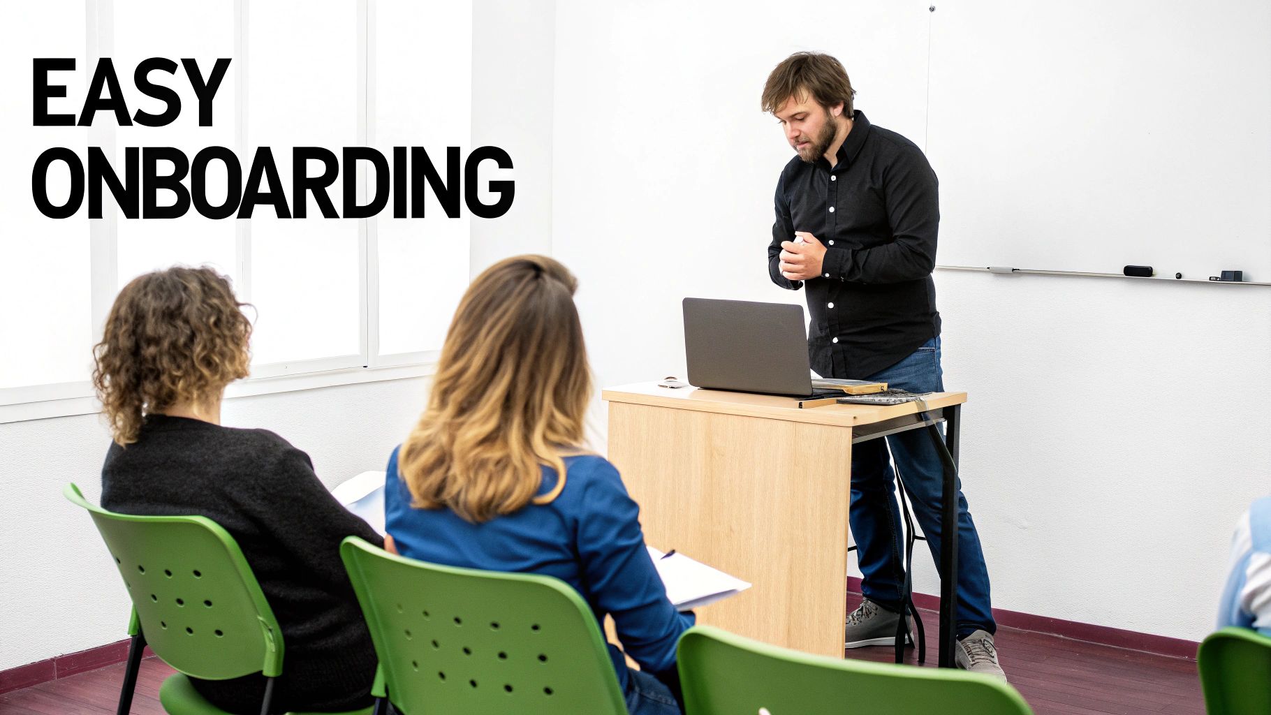 A man presents "EASY ONBOARDING" content to two women in a bright classroom setting.