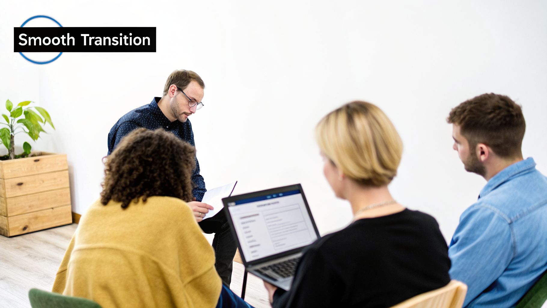 Diverse group of professionals collaborating in a modern office, with one person using a laptop.