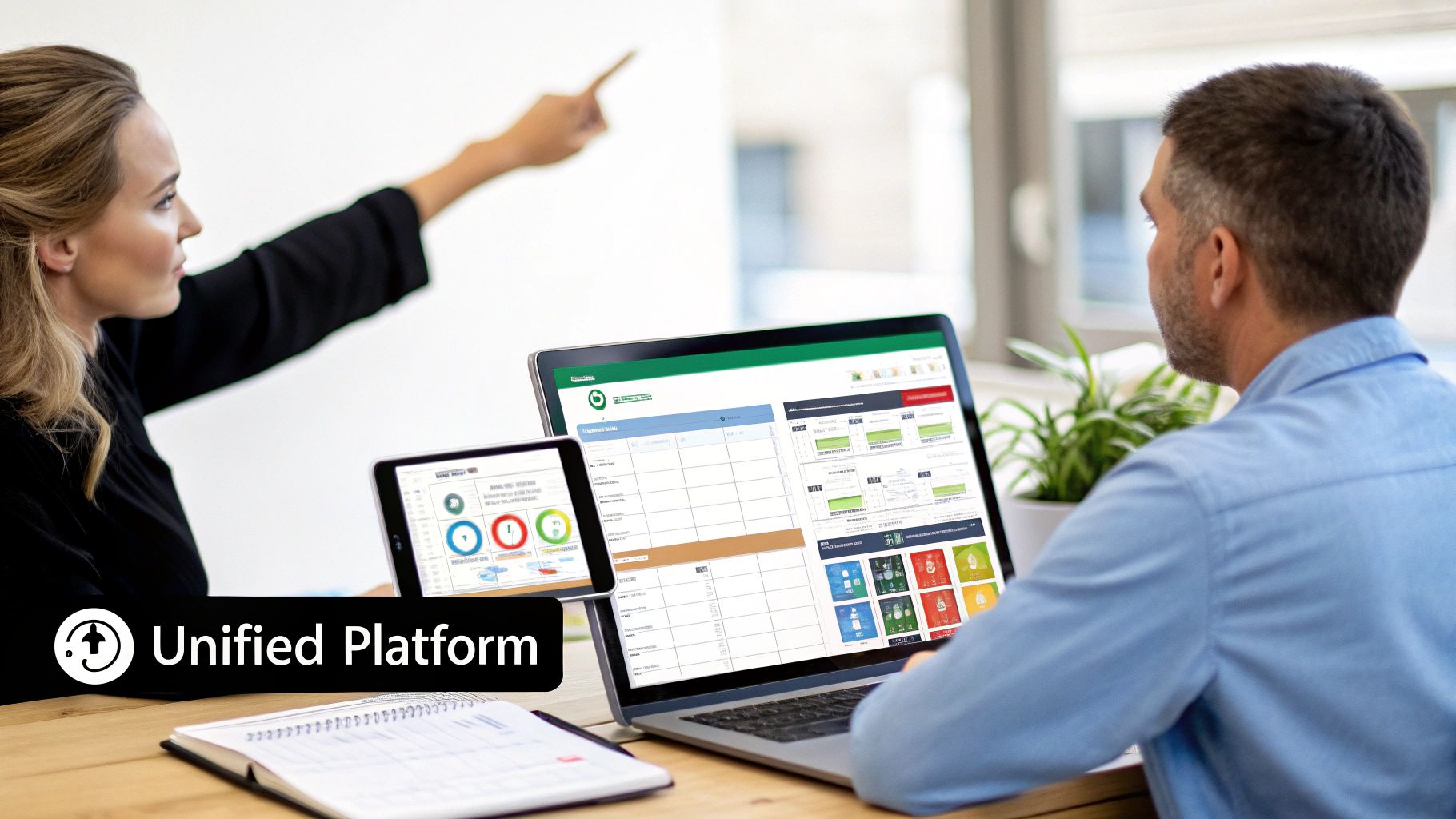 Two professionals collaborating with a unified platform displayed on a laptop and tablet in an office.